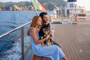 Coppia con il cagnolino seduta su un ponte di un traghetto in navigazione